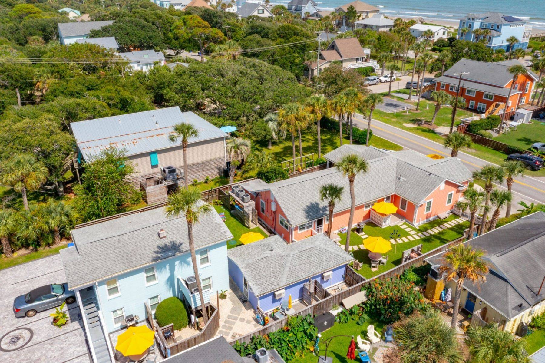 Aerial view of The Rather Shacks compound on Folly Beach, a cluster of colour-painted cottages with yellow umbrellas