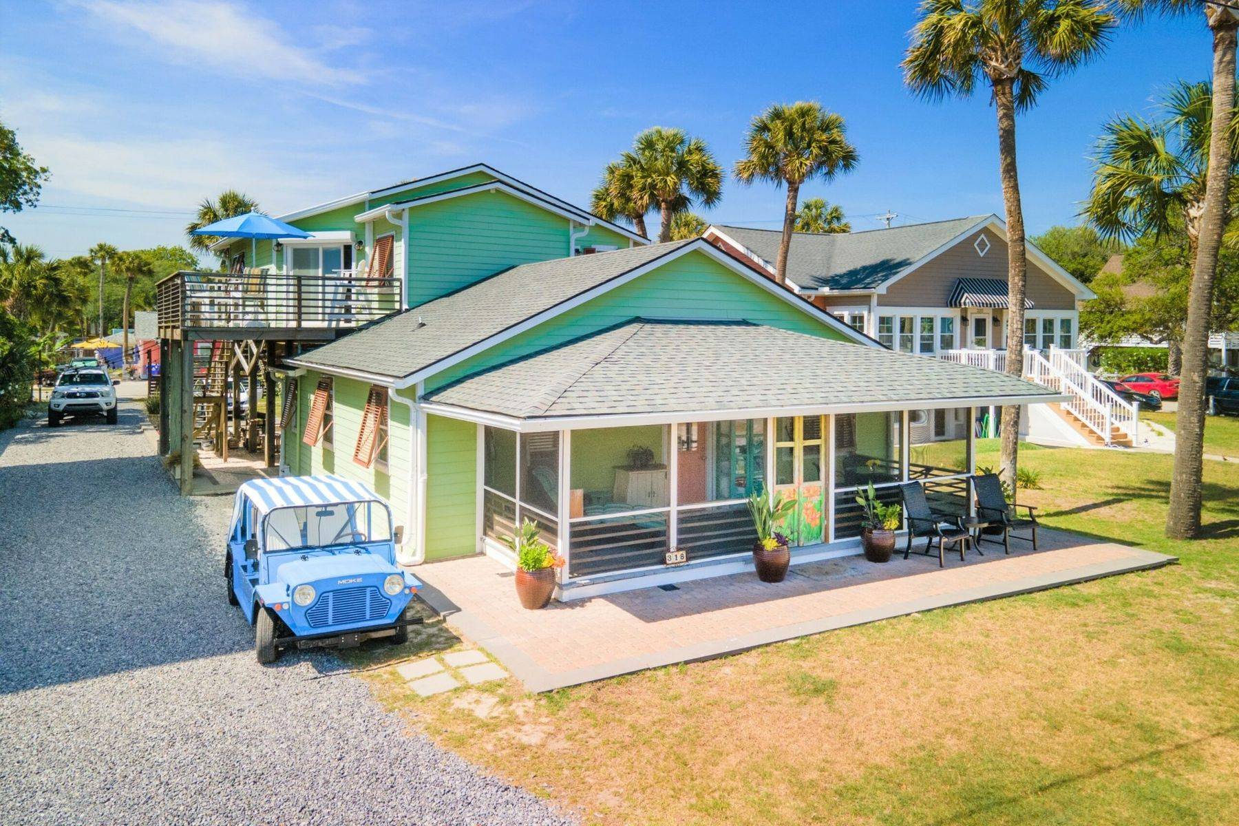 One of The Rather Shacks cottages today, a restored green beach house with a covered porch and a blue golf cart parked outside